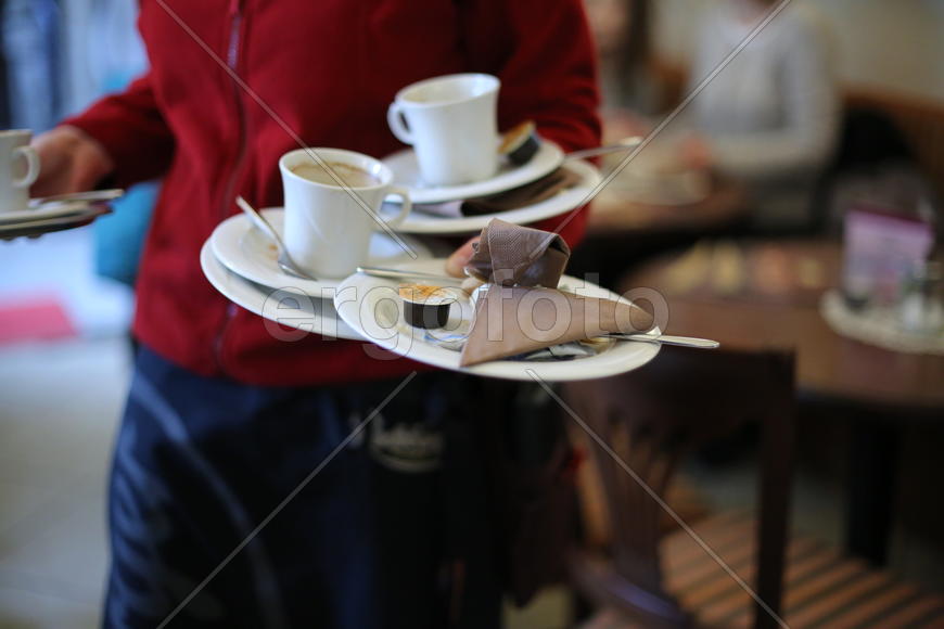 Официант с посудой в руках