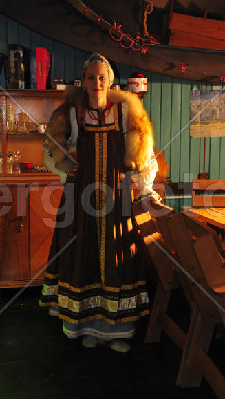 Девушка в русском сарафане в домашнем интерьере