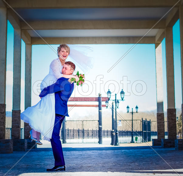 Жених держит на руках радостную невесту