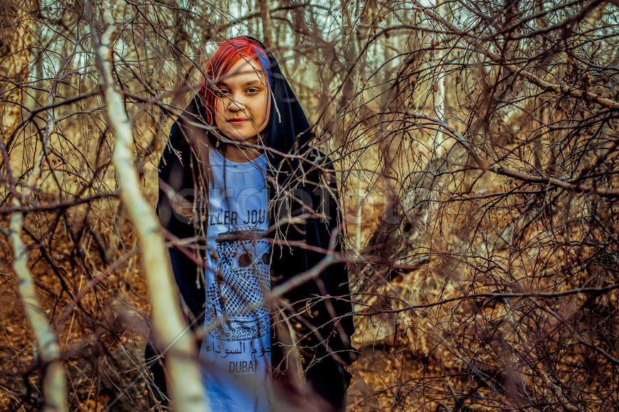 Девушка с яркими волосами в ветвях деревьев