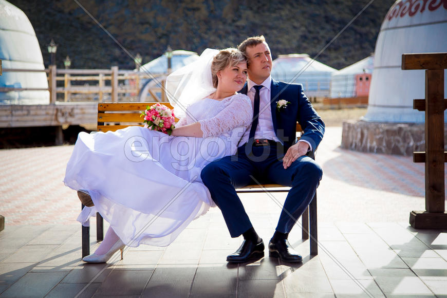 Жених и невеста сидят на скамье в обнимку
