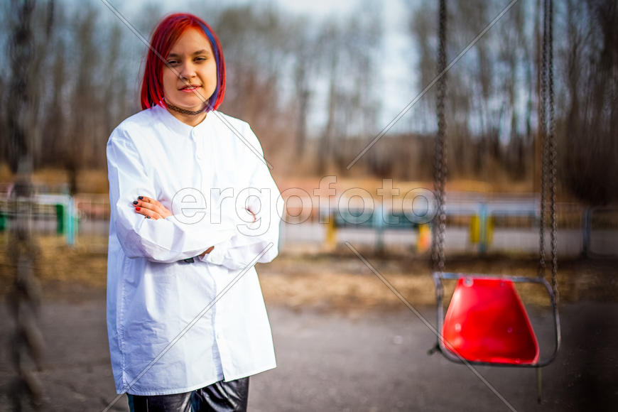 Девушка стоит около качелей