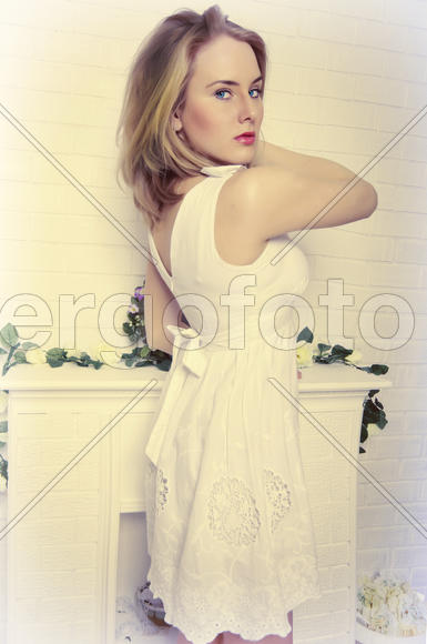Beautiful blond girl with blue eyes in a white dress looks strictly on a white background