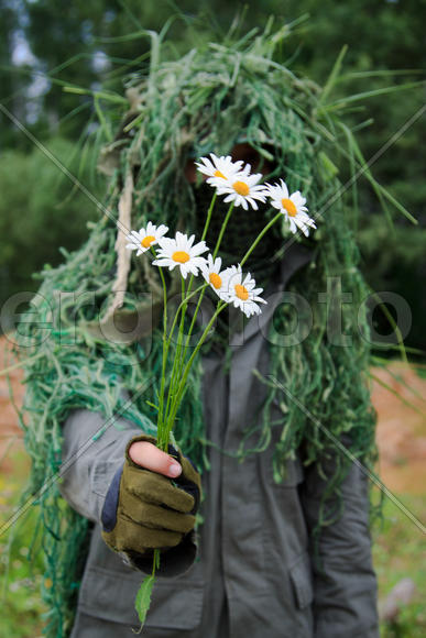 Снайпер в масировочном костюмегилли с букетом ромашек