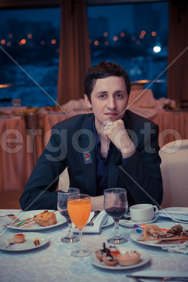 Парень-брюнет сидит за столом