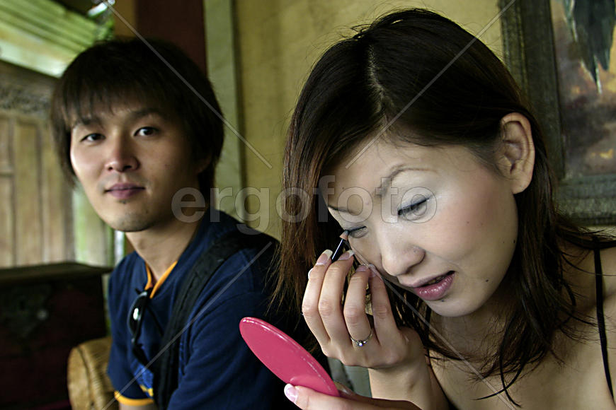 Девушка красится, а мужчина наблюдает за фотографом