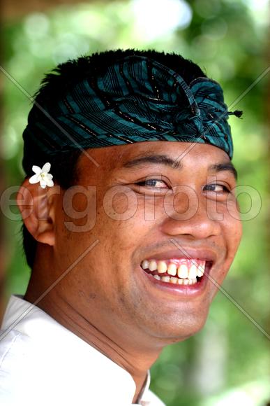 Мужчина с цветком за ухом улыбается