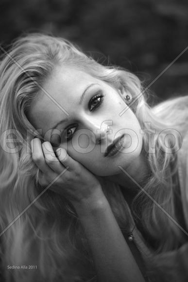 Грустная и красивая светловолосая девушка склонив голову смотрит в камеру