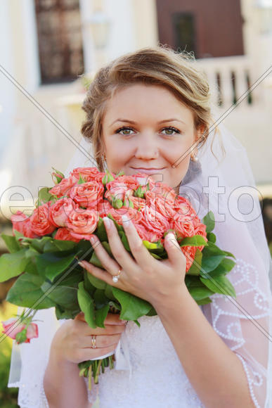Молодая невеста держит большой свадебный букет из роз