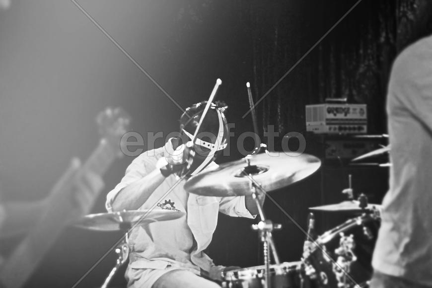 Барабанщик в маске играет на концерте