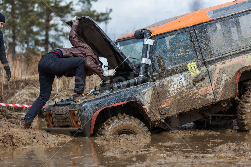 Человек смотрит под капот внедорожника на соревнованиях "Уральская грязь 2015"