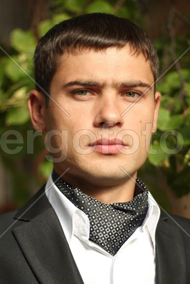 Молодой мужчина на фоне листьев