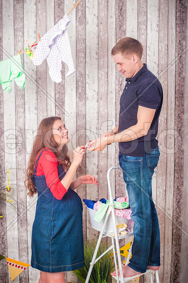 Муж и беременная жена развешивают вещи