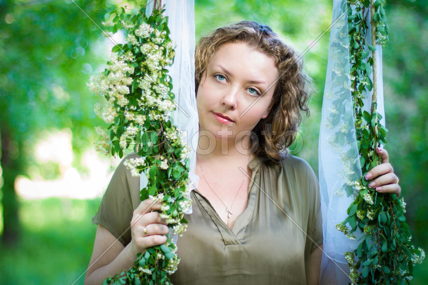 Девушка на качелях, обвитых зеленью