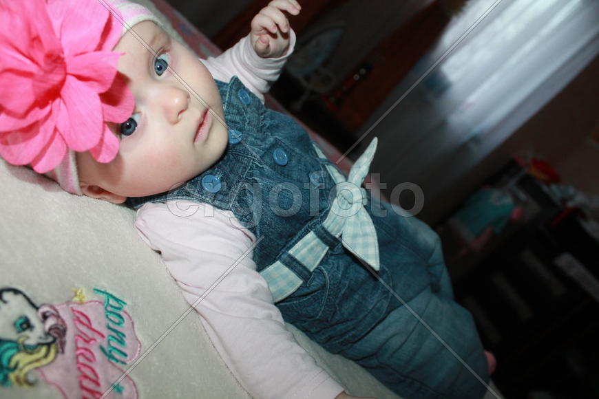 Маленькая девочка с бантиком лежит на кровати. Анфиса