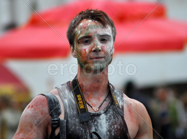 Парень в разноцветных красках с фотоаппаратом