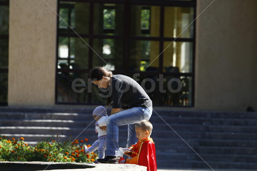 Молодая мама с двумя детьми на прогулке 