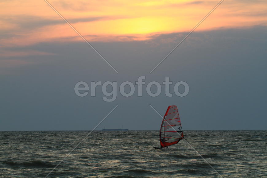 Серфингист в море на закате 