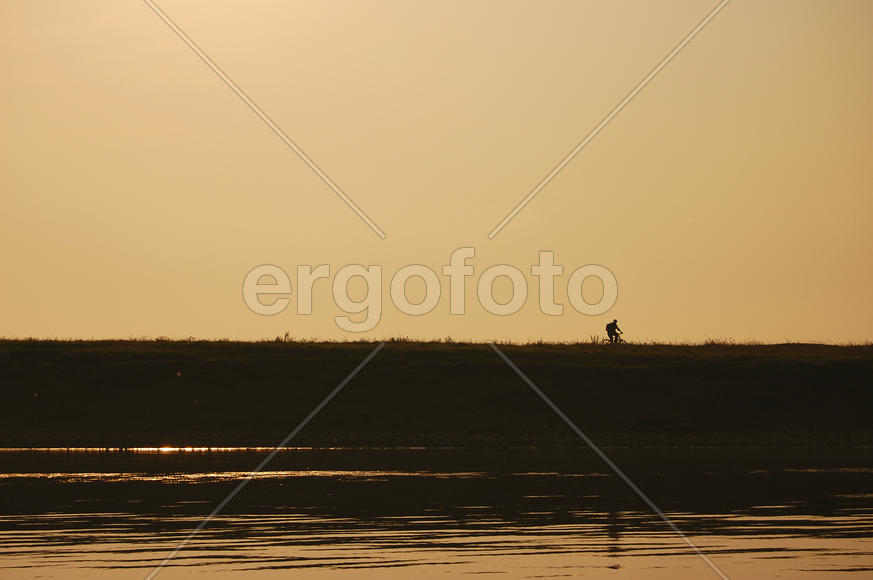 Рыбак на рассвете едет на рыбалку на велосипеде