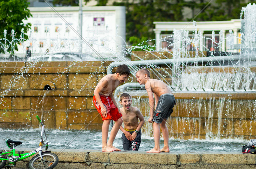 Дети купаются в фонтане.