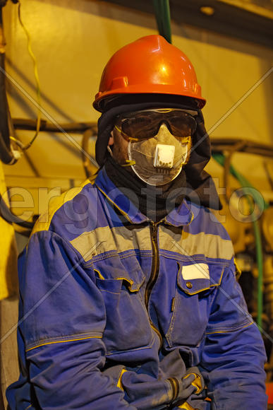The worker in overalls and a respirator. Protective attire of technical workers