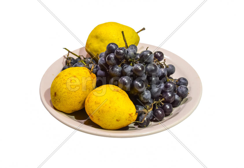 Желтая груша и виноград на тарелке.