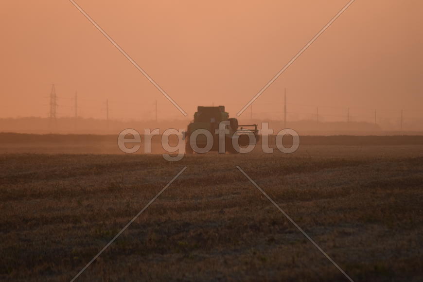 Harvesting by combines at sunset. Agricultural machinery in operation.