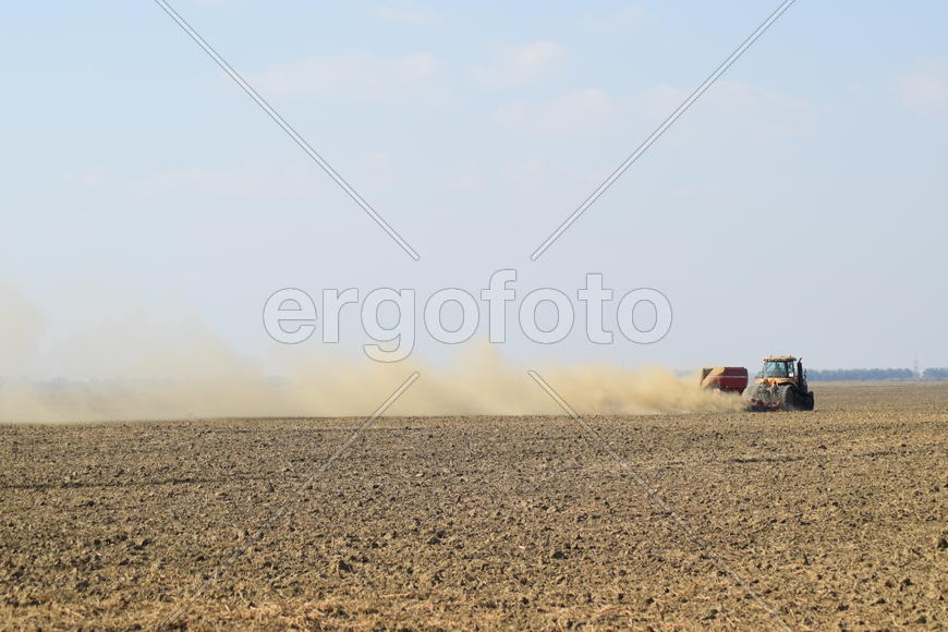 Russia, Temryuk - 19 July 2015: Tractor rides on the field and makes the fertilizer into the soil. C