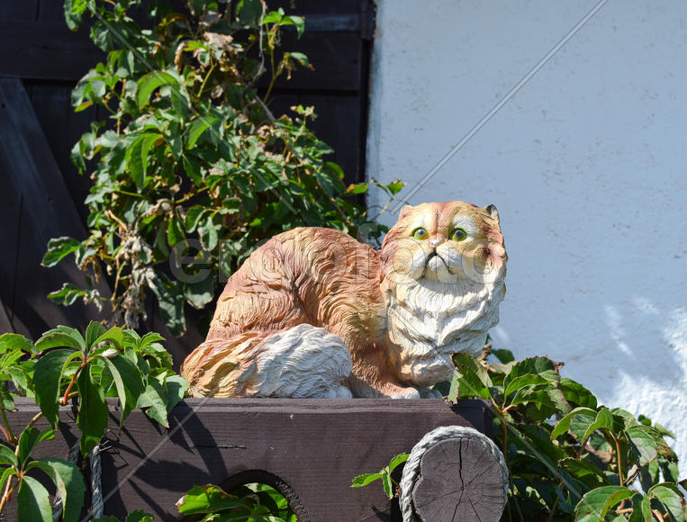 Статуэтка кошки из гипса и пластика на заборе.