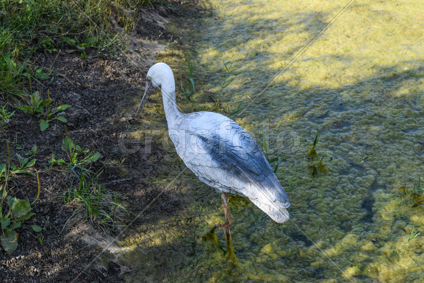 Фигурка аиста возле пруда. Искусственные животные.