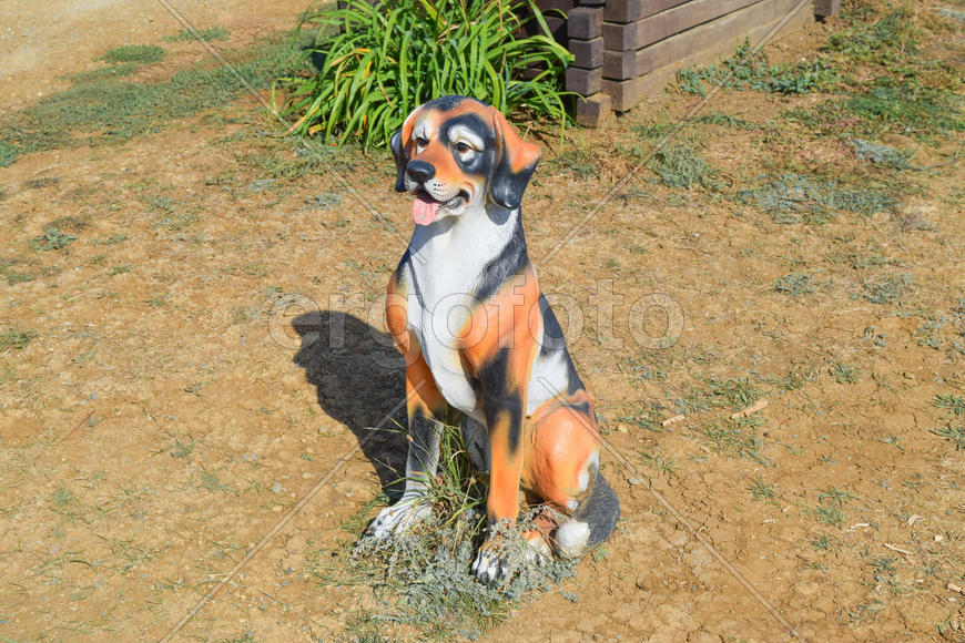 Декоративная фигурка собаки в саду 