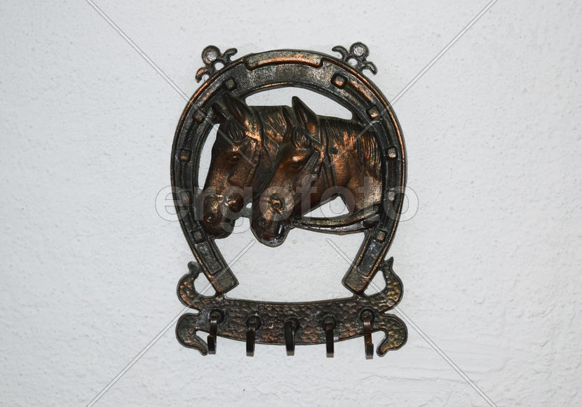 Вешалка для одежды украшенная изображением подковы и головы лошадей.