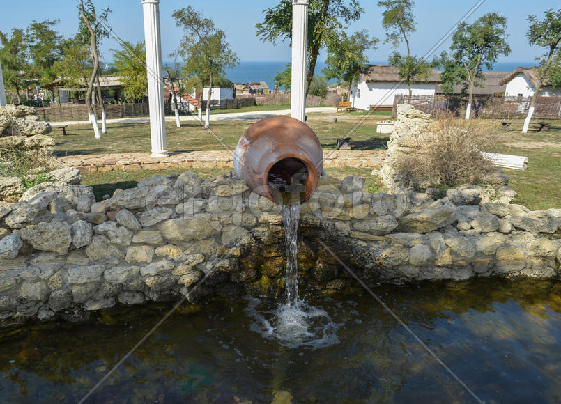 Вода, льющейся из кувшина в пруд. Декоративный пруд.