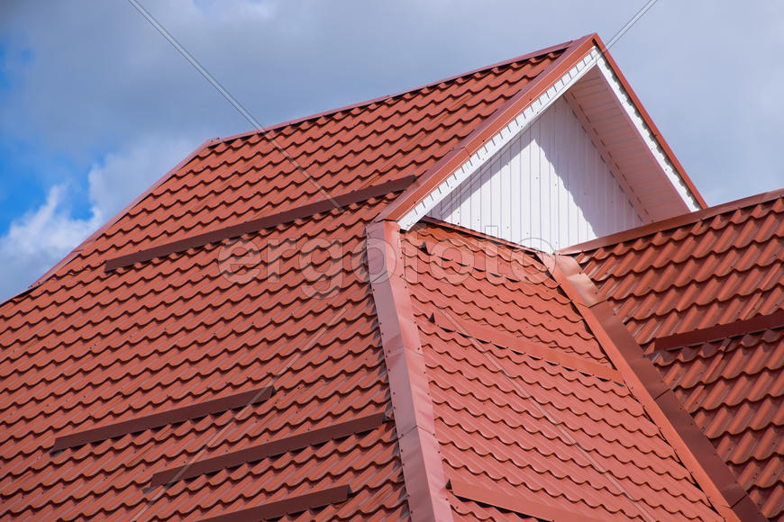 The roof of corrugated sheet red, orange. Roofing of metal profile wavy shape.