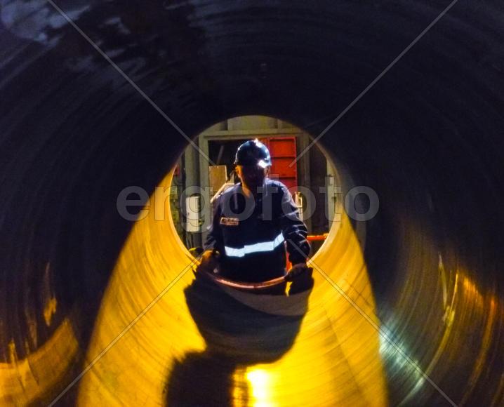 Работник смотрит в трубу. Строительство газопровода.