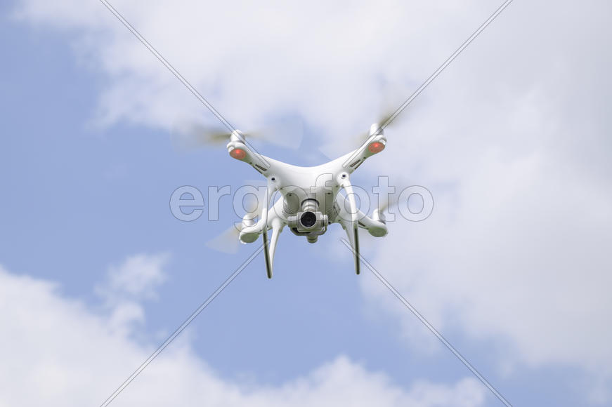 Flight quadrocopters white against the blue sky with clouds