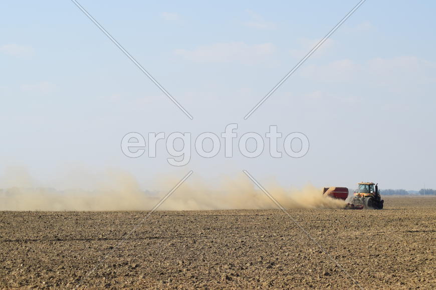 Russia, Temryuk - 19 July 2015: Tractor rides on the field and makes the fertilizer into the soil. C