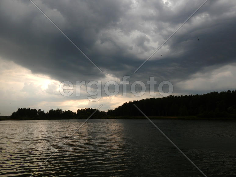 Черные грозовые тучи на озере