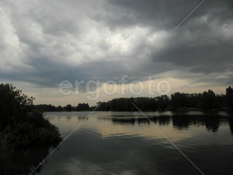 Черные грозовые тучи на озере
