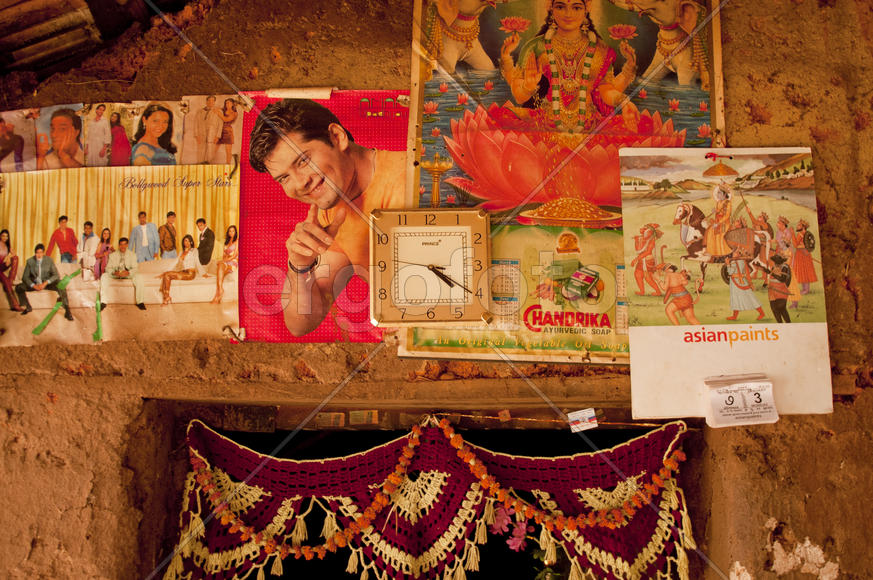 Clock, calendar and magazine clippings over the entrance to the rural housing in India