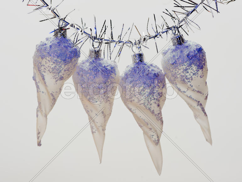 Four Christmas toys in the form of icicles hanging on a branch