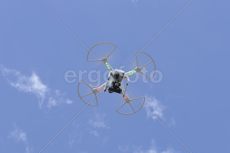 Drone with a video camera flying in the blue sky