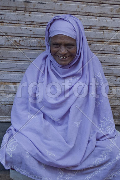 An elderly Muslim woman sitting on a street in Mumbai