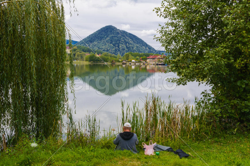 Рыбак с удочкой на берегу горного озера