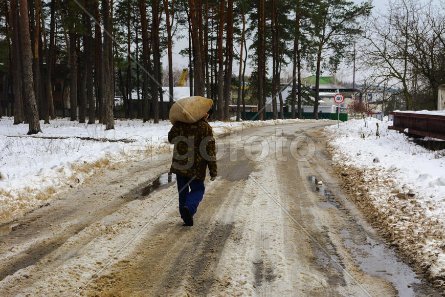 Человек несет большой мешок по дороге покрытой снегом 