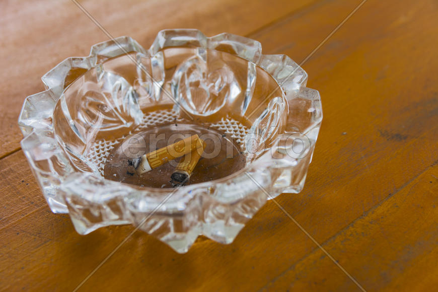 Грязная пепельница с окурками на столе