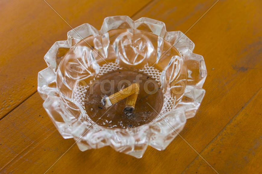 Грязная пепельница с окурками на столе