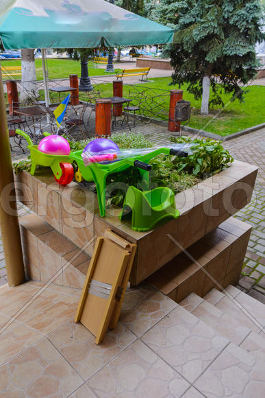 Детские игрушки и горшки на цветочной клумбе 