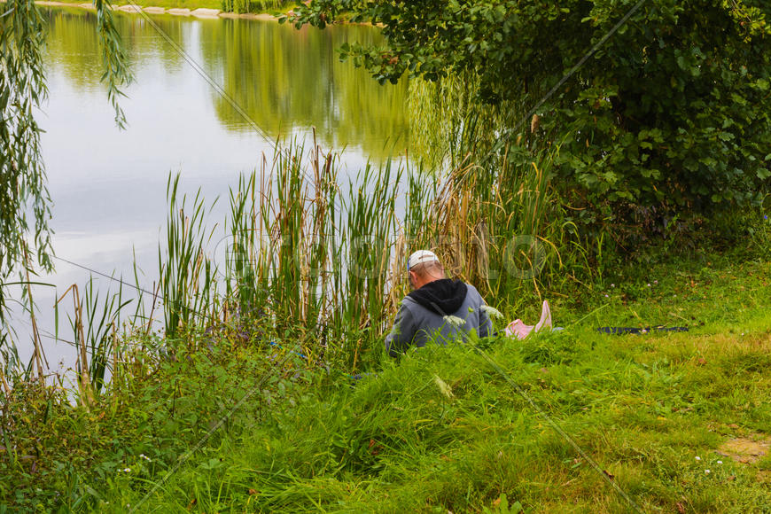 Рыбак с удочкой на берегу горного озера
