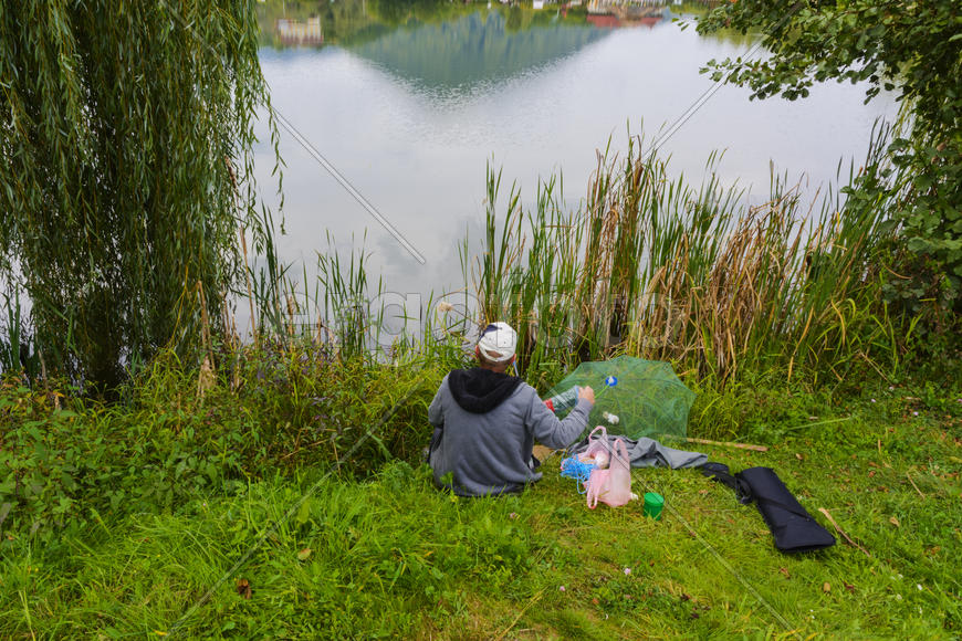 Рыбак с удочкой на берегу горного озера